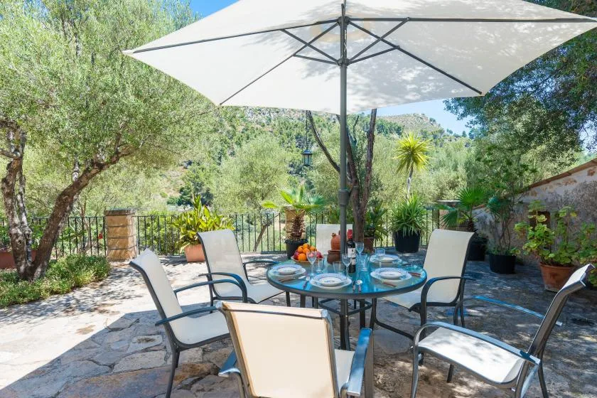 An outdoor patio dining area with a table and seating beneath a large umbrella.