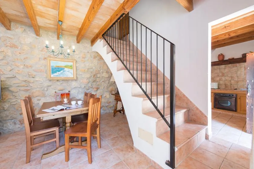 A dining area beside a staircase, with a wooden table and chairs.