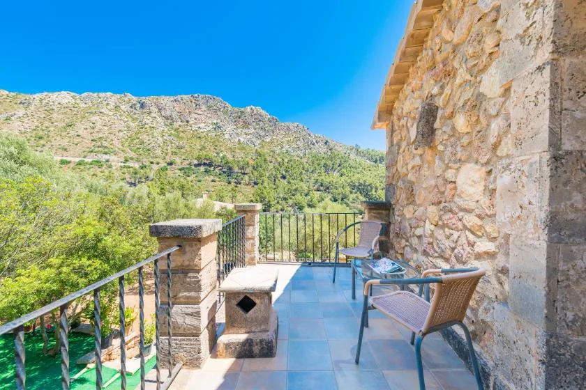 A stone terrace with outdoor seating overlooks a green hillside.
