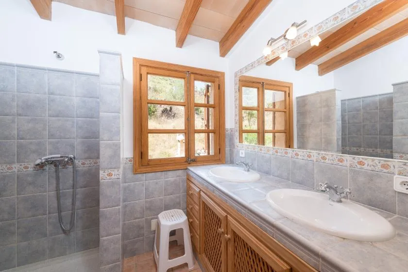 A bright bathroom with a long vanity, two sinks, and a separate shower.