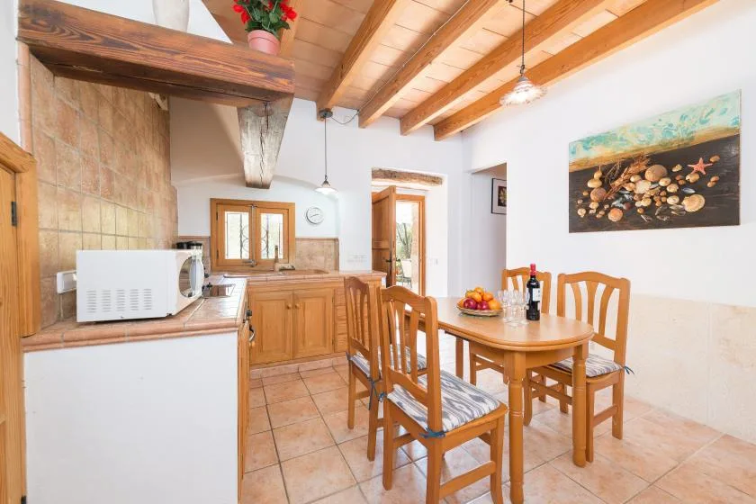 A warm dining and kitchen area with wooden furniture and exposed ceiling beams.