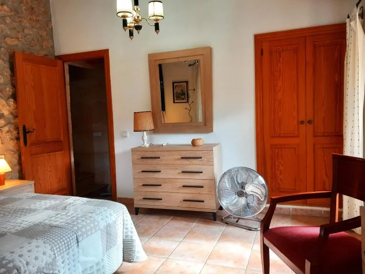 A bedroom with a bed, dresser, and wooden wardrobe.