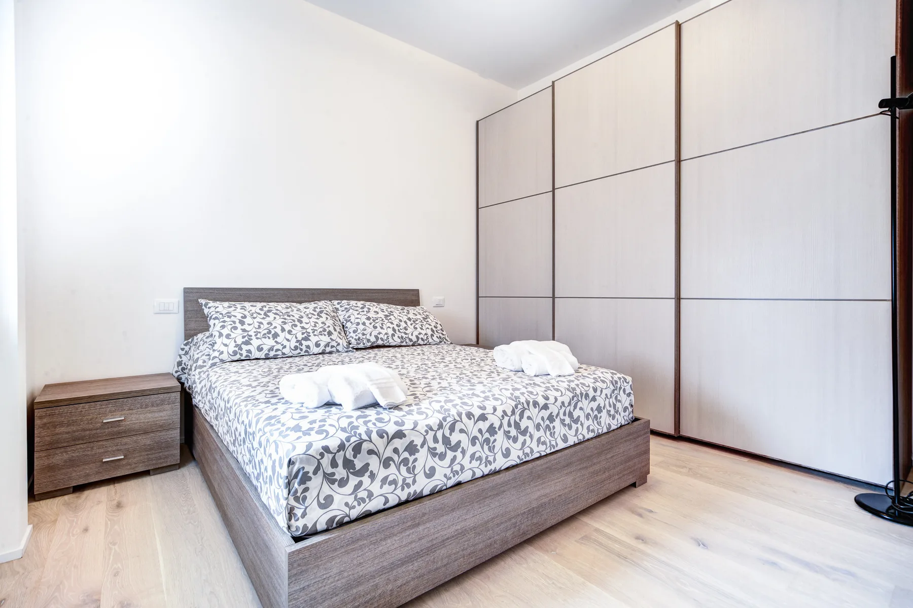 Un dormitorio con una cama estampada junto a grandes armarios empotrados.
