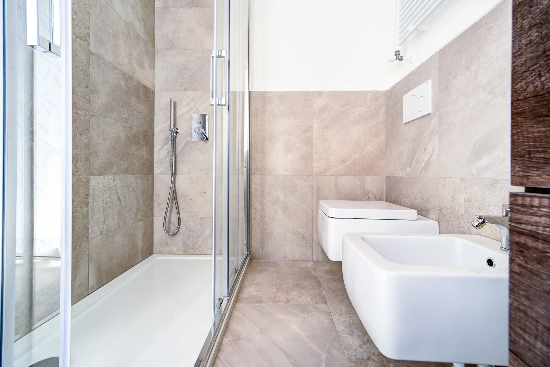 Un baño alicatado con ducha de vidrio y accesorios blancos.