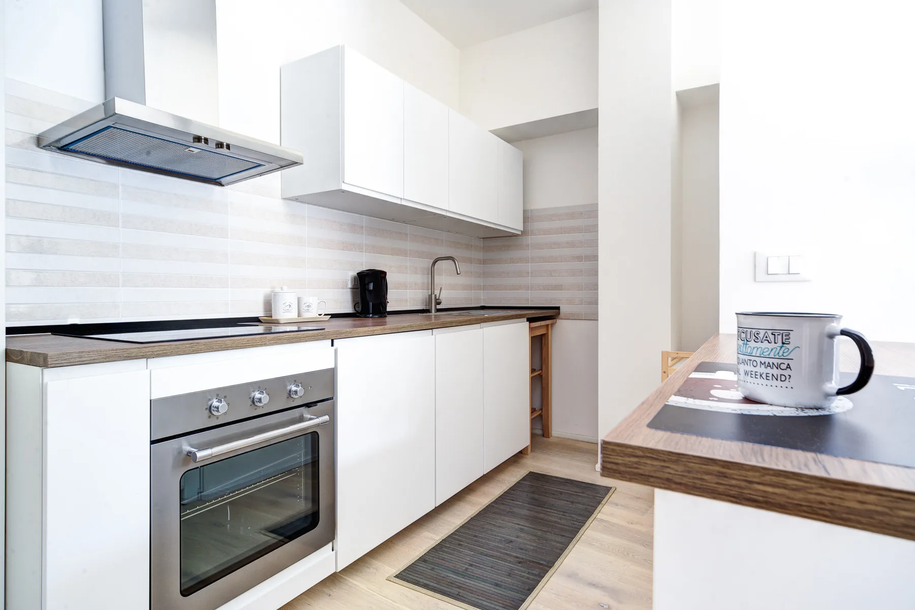 Una cocina moderna y luminosa con gabinetes blancos, una encimera y un horno.