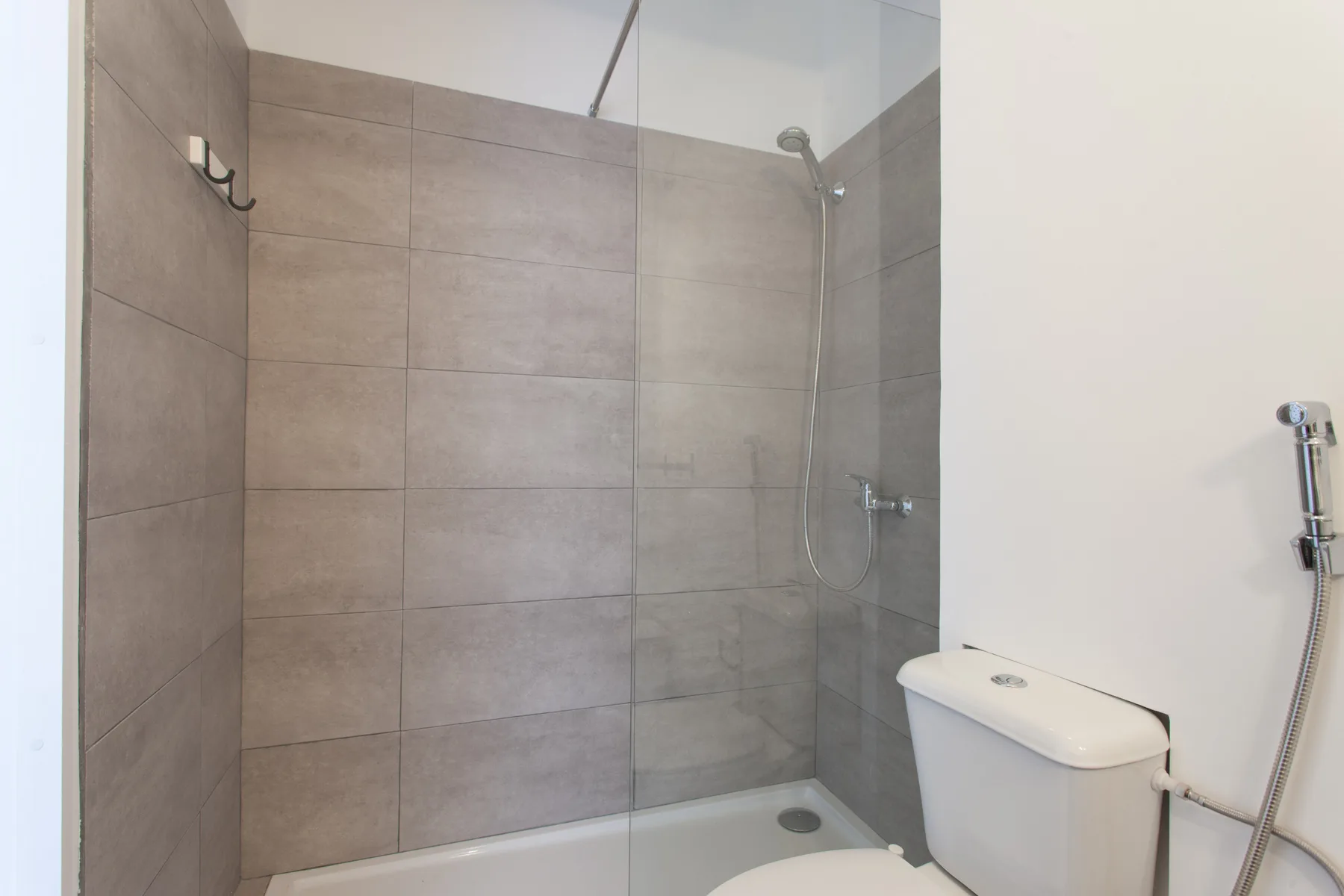 A tiled bathroom with a shower and toilet.