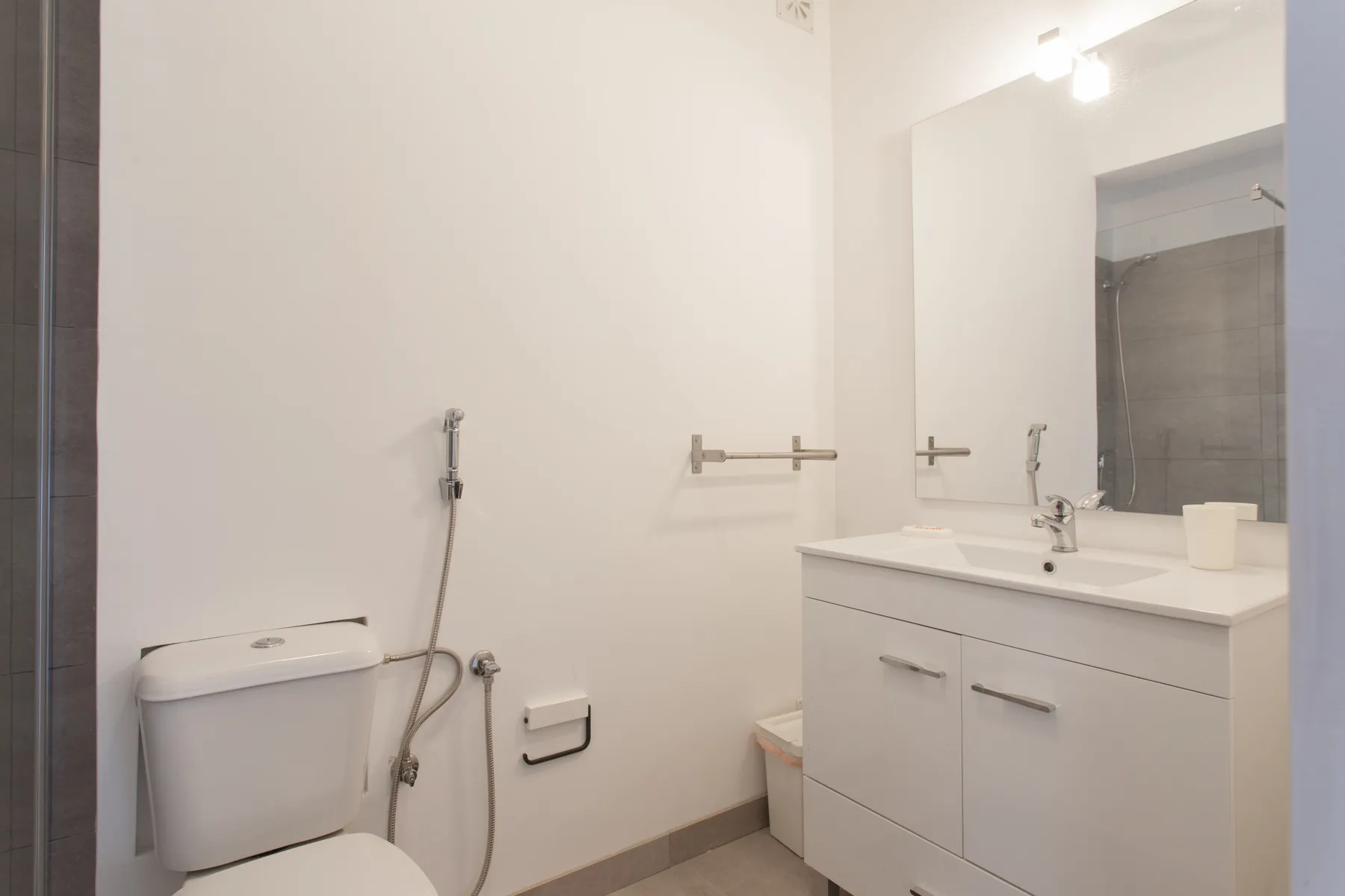 A bright bathroom with a vanity, mirror, and toilet.