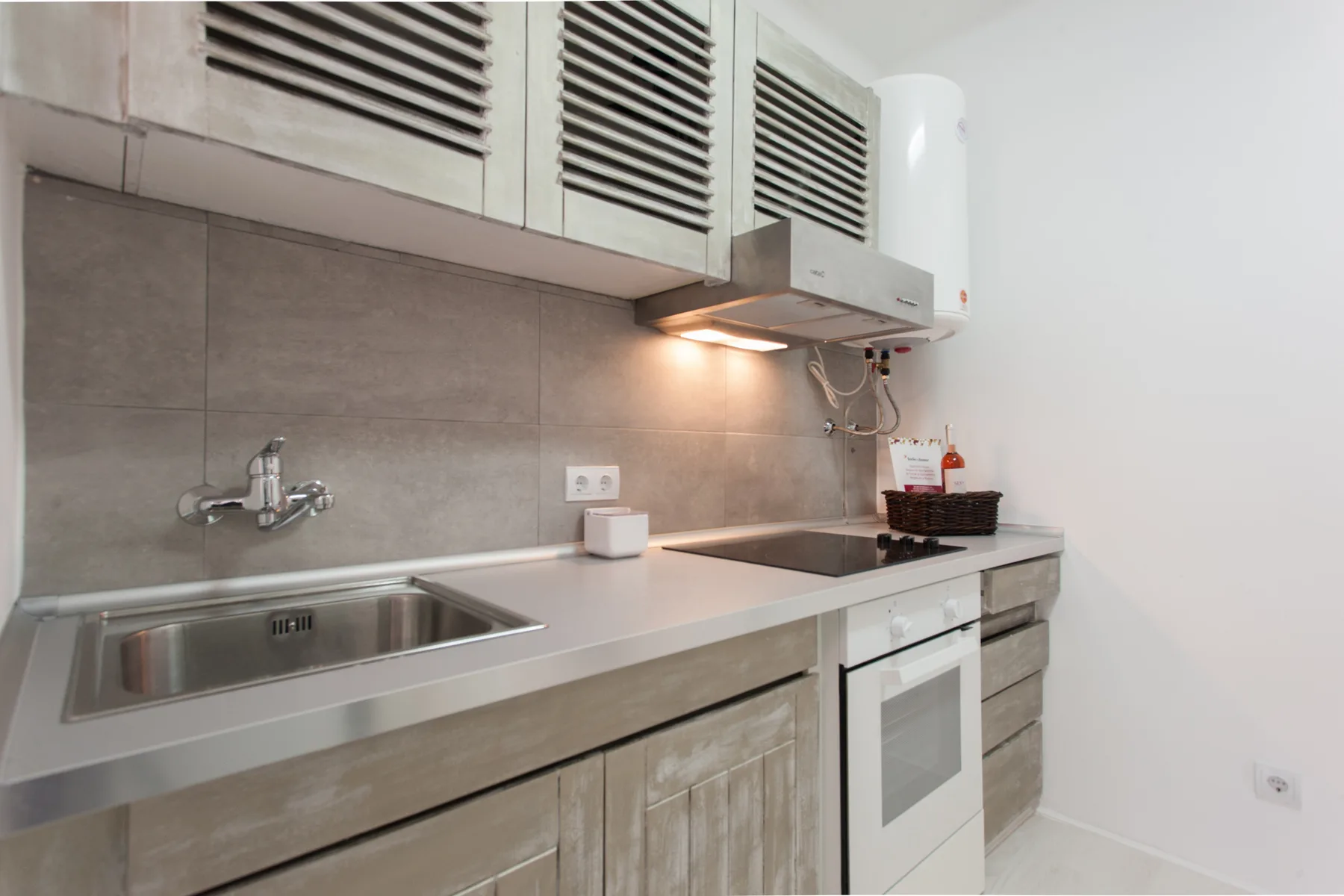 A compact kitchen with a countertop, sink, and cooktop.
