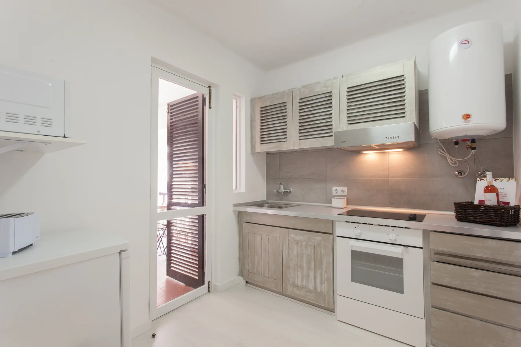 A compact kitchen with light cabinetry, a cooktop, and an oven.