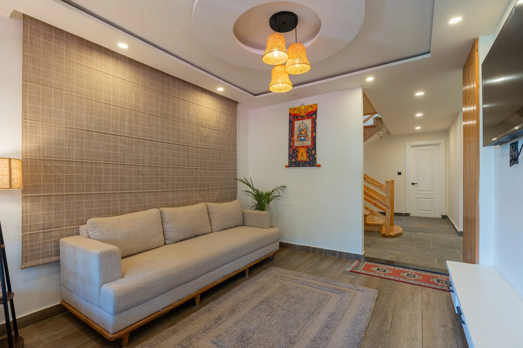 A living room with a long sofa, rug, and colorful wall hanging.