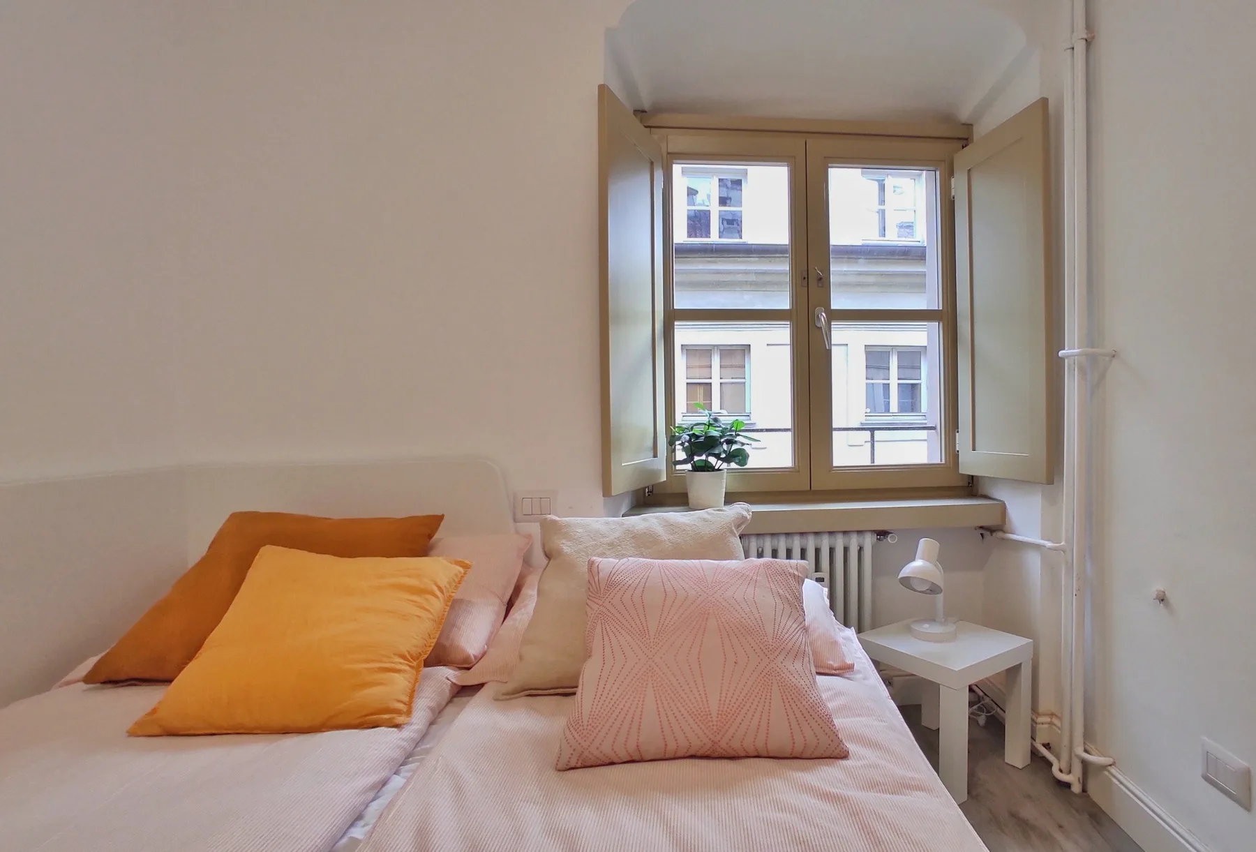 A bedroom with a bed beneath a window and pale bedding.