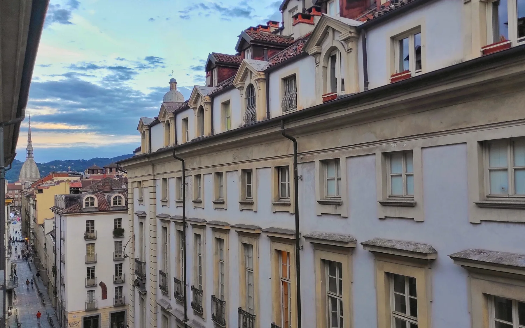 An exterior view of adjoining buildings with rows of windows beneath a cloudy sky.