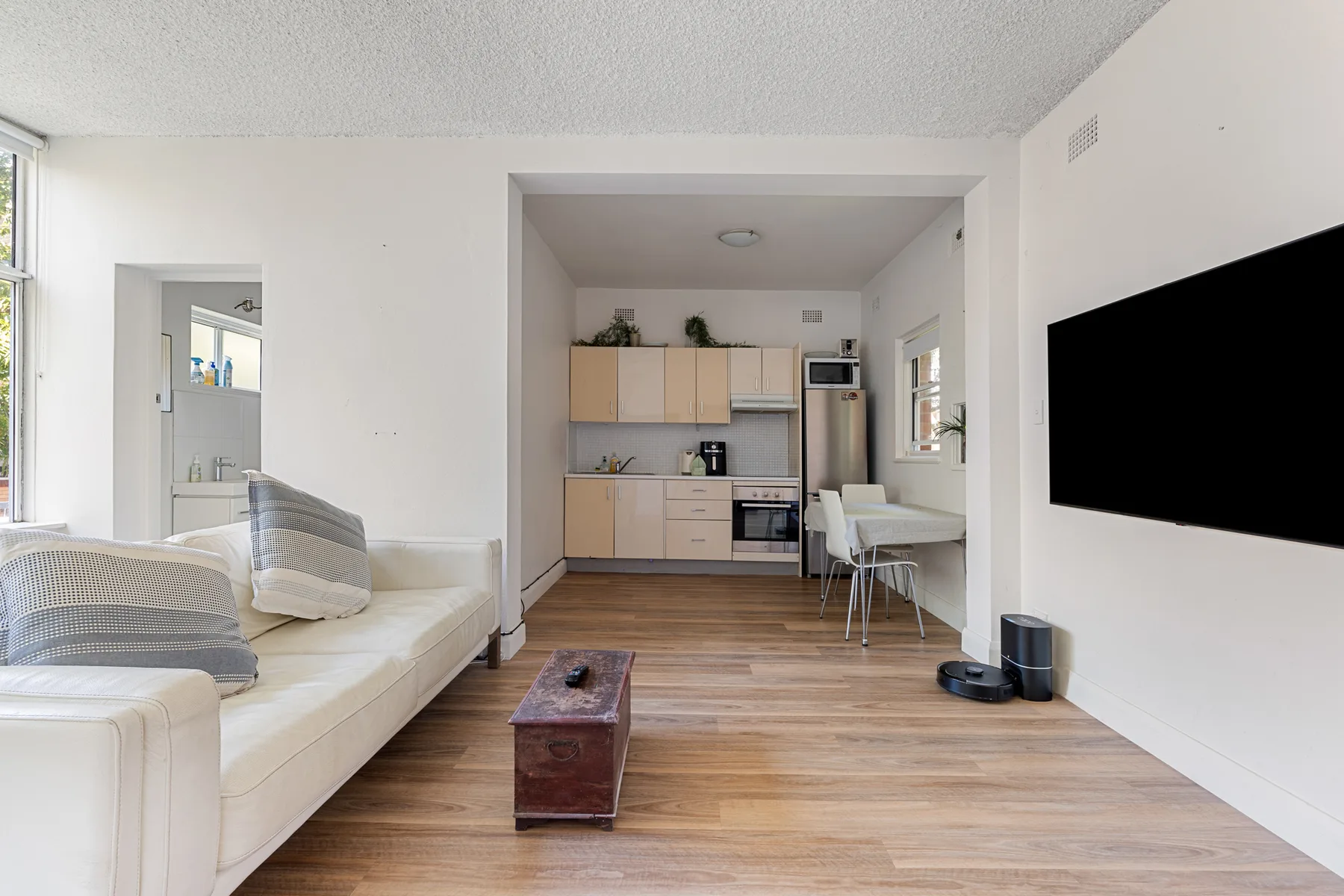 An open-plan living area with seating, a coffee table, and a kitchen.