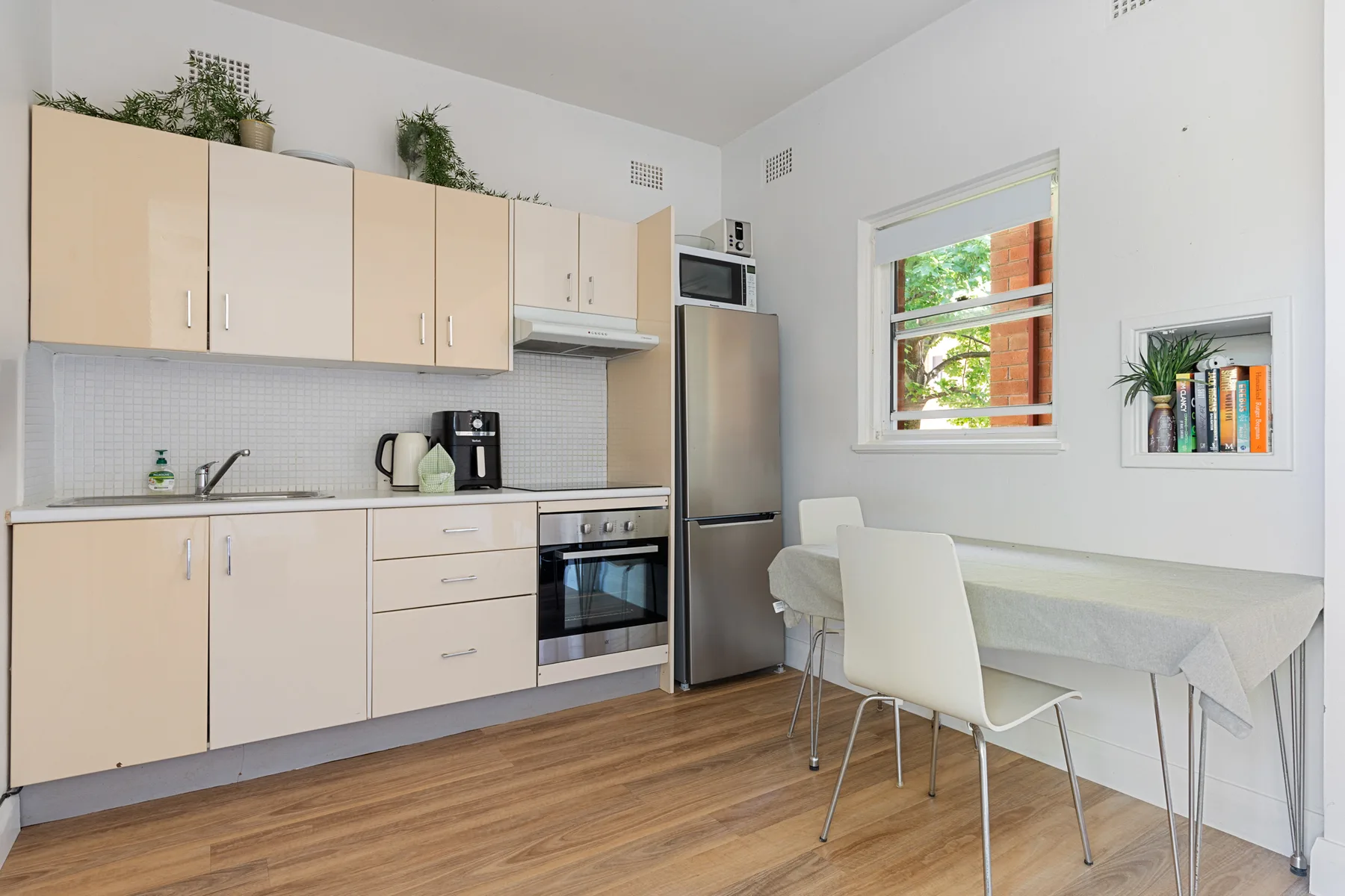 Cocina y comedor luminosos, con armarios claros y una mesa junto a la ventana.