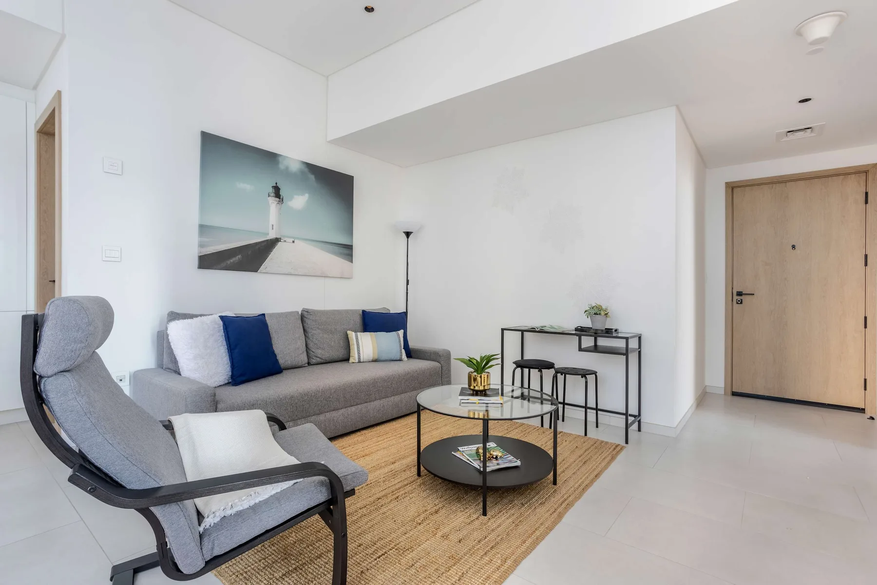 A bright living room with a gray sofa, lounge seating, and a round coffee table.
