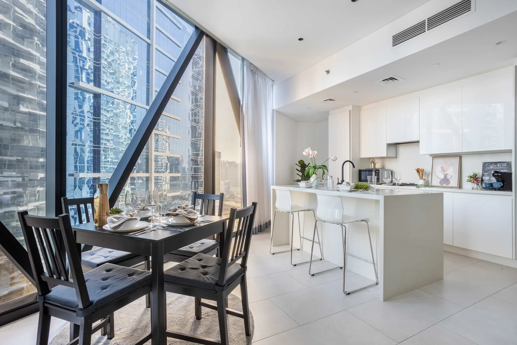 A bright open-plan dining area and kitchen beside tall windows.
