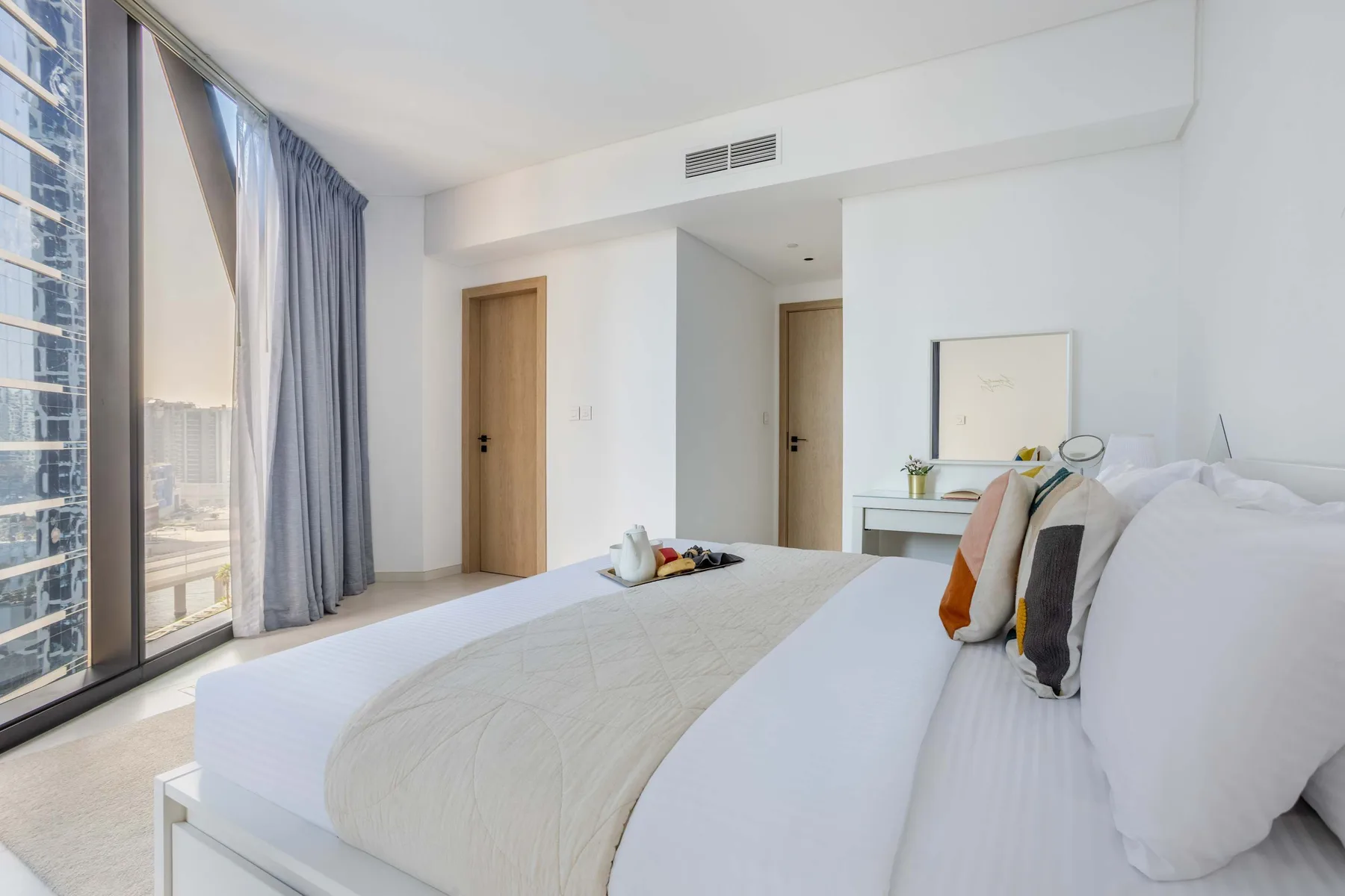 Un dormitorio luminoso con una cama grande junto a ventanales.