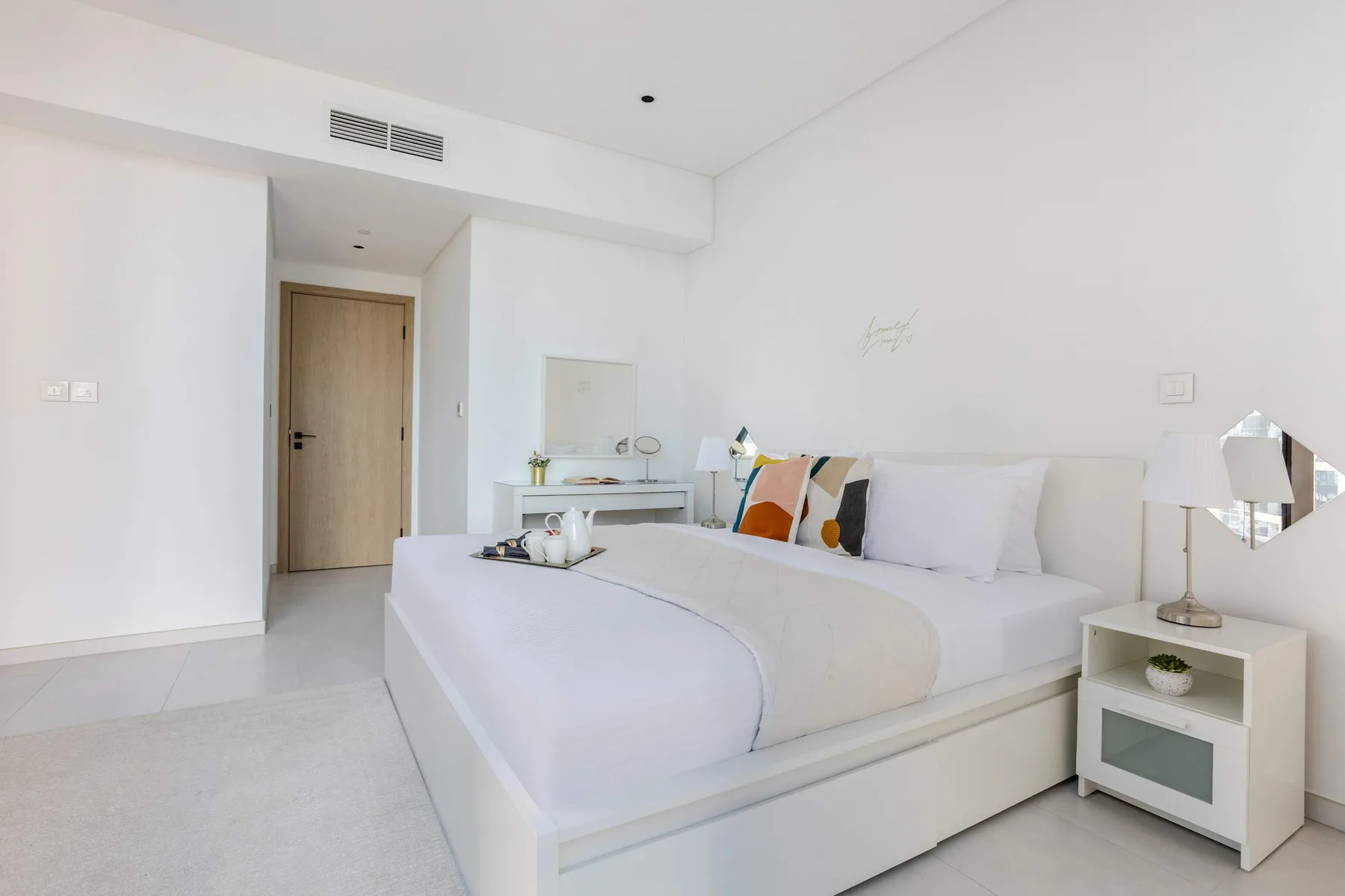 A bright bedroom with a neatly made bed and bedside tables.