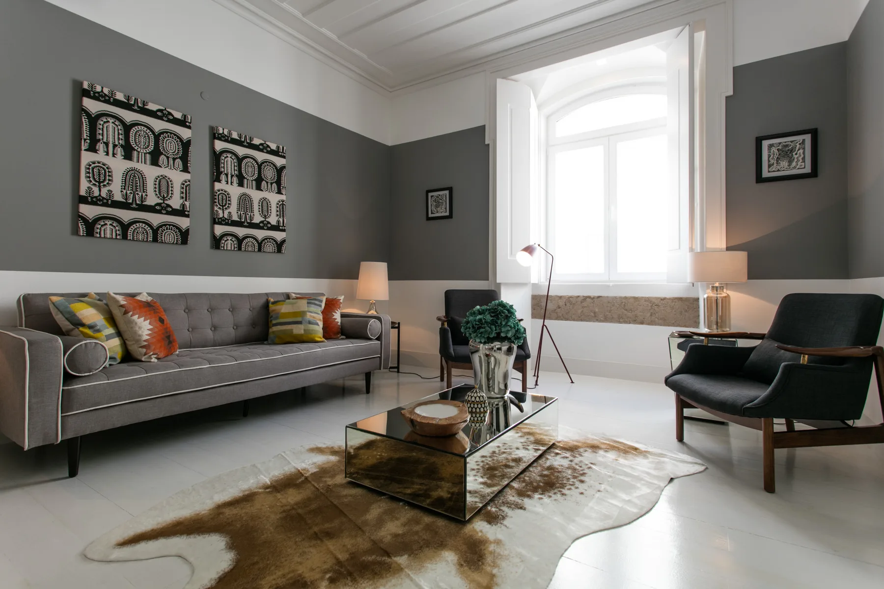 A living room with a gray sofa, armchairs, and a glass coffee table.