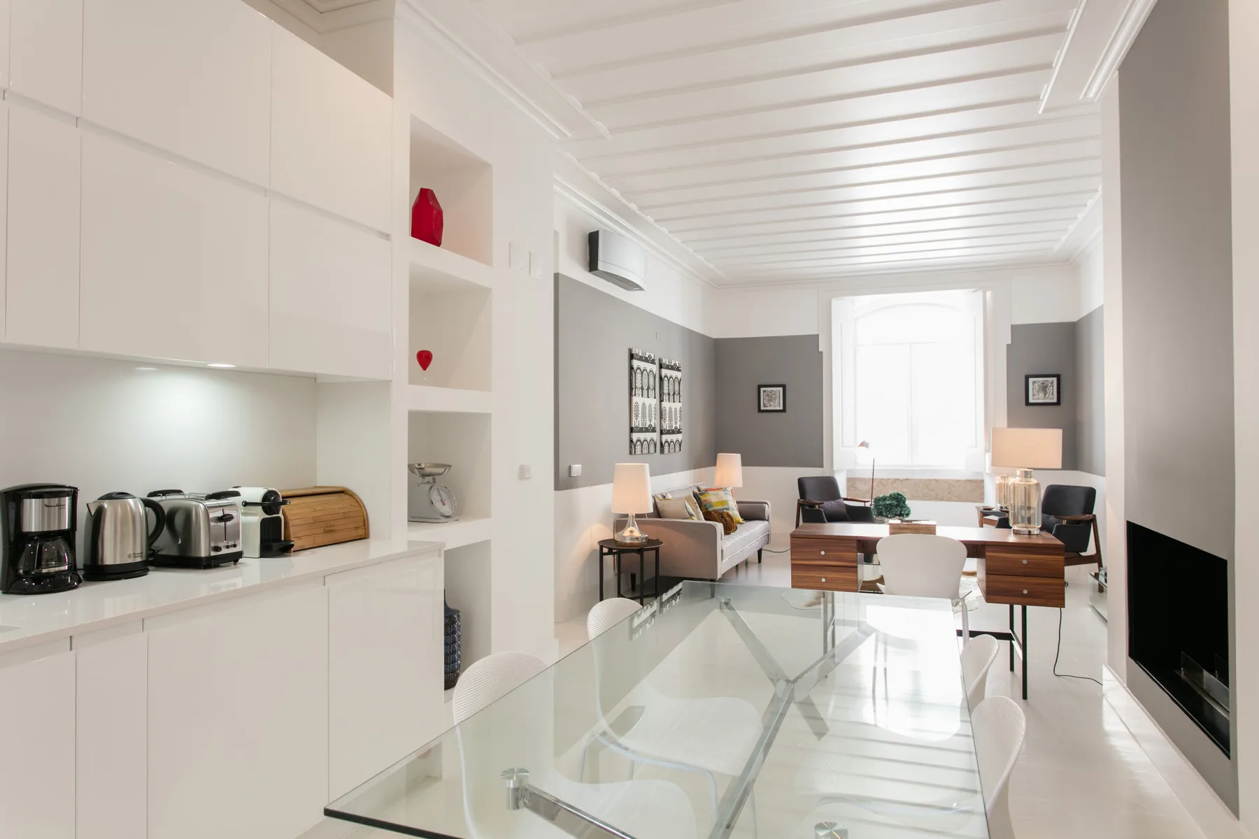 Bright living and dining room with a glass table and seating by the window.