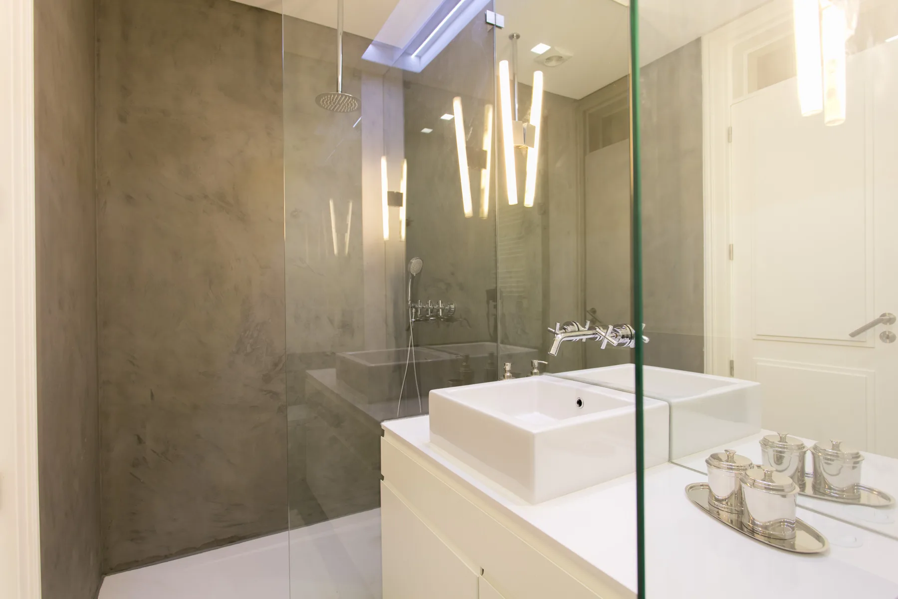 A bright bathroom with a glass shower and a white sink.