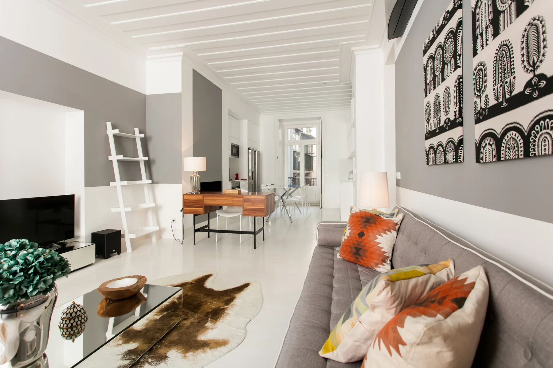 A bright living room with a television, seating, and a dining area in the background.