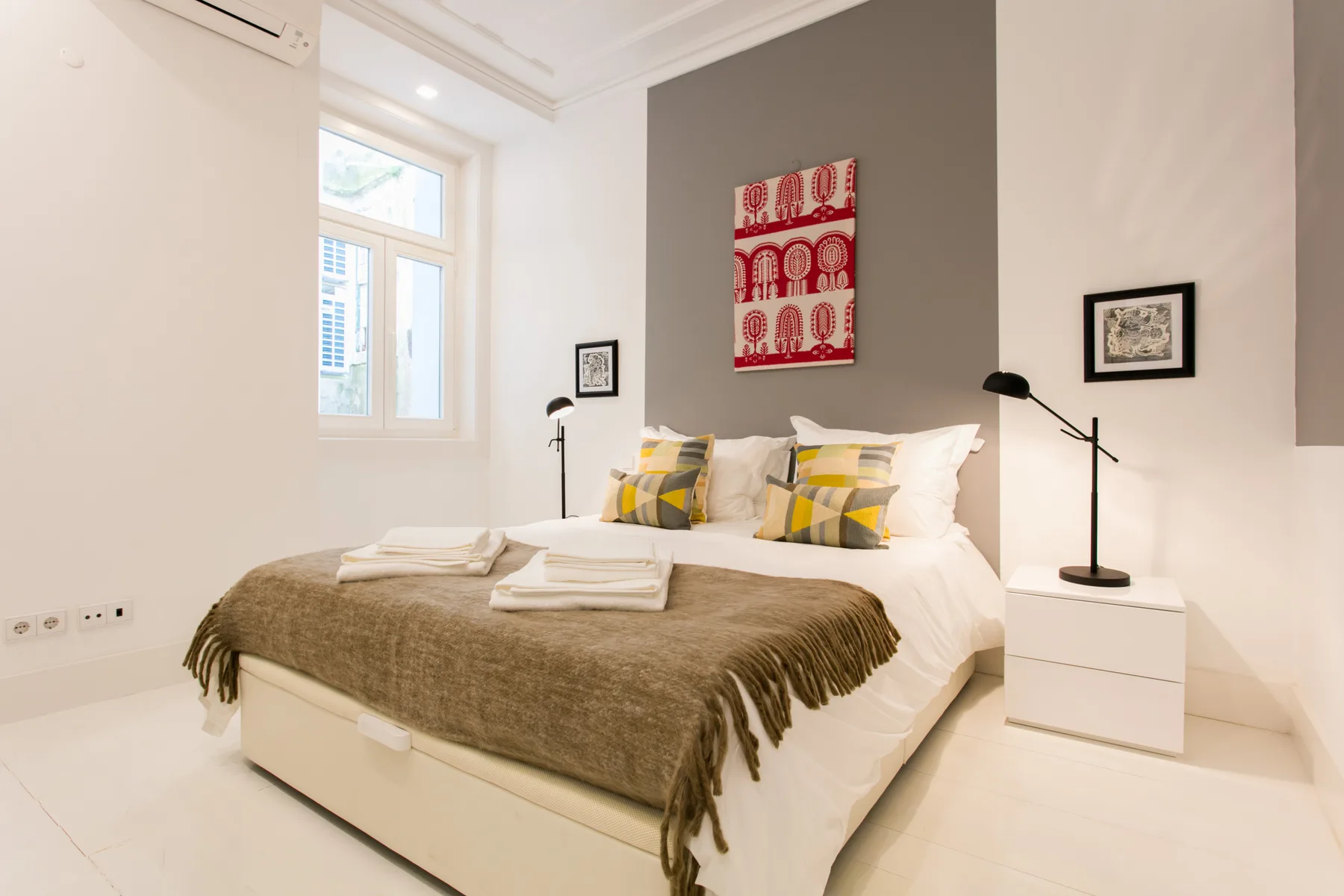 A bright bedroom with a neatly made bed and bedside tables.