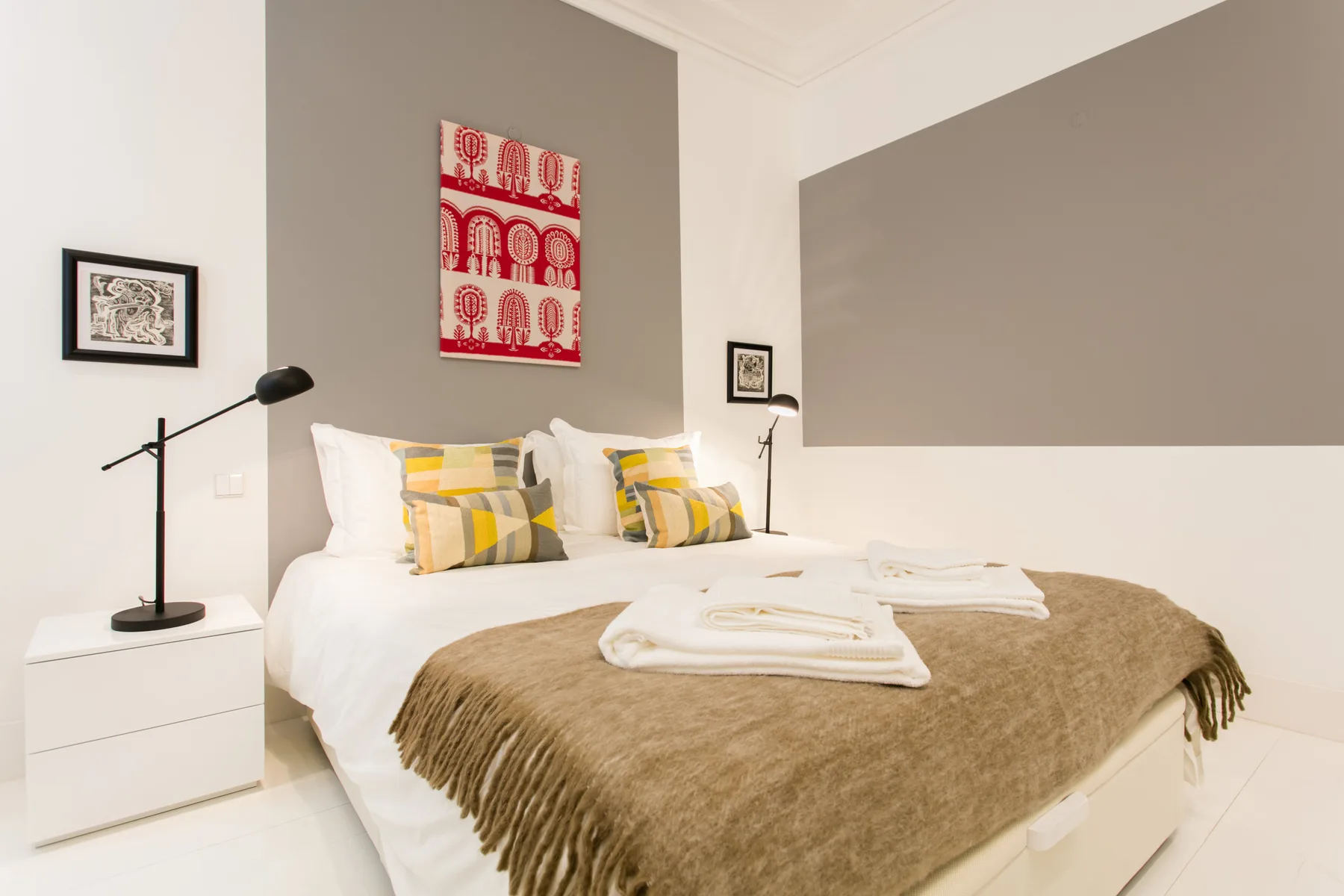 A bedroom with a neatly made bed and folded towels.