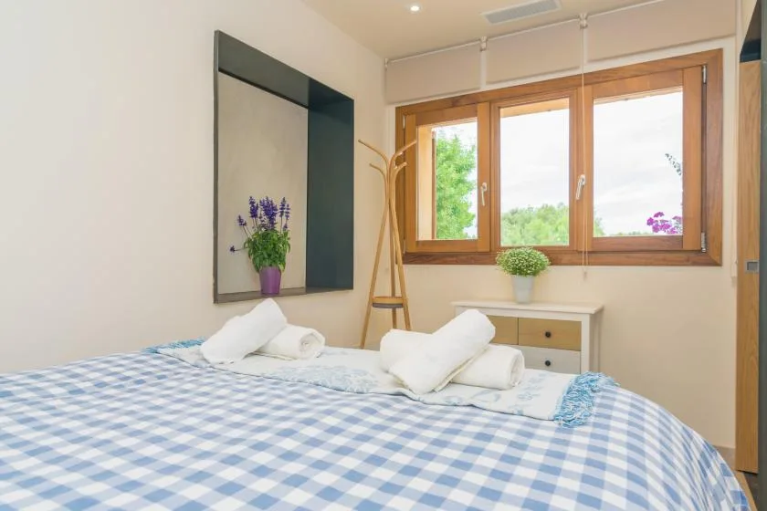 A bedroom with a blue-and-white checkered bedspread and wooden-framed windows.