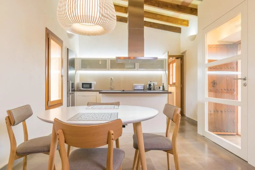 A dining area with a round table beside an open kitchen.