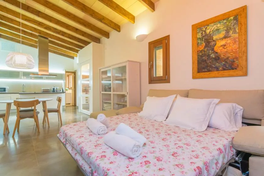 A bedroom with a floral bedspread and exposed wooden ceiling beams.