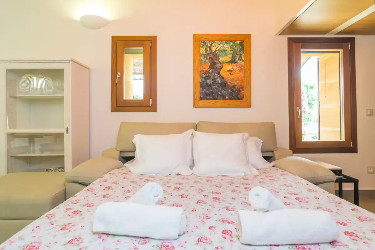 A bedroom with a floral bedspread and two folded towels.
