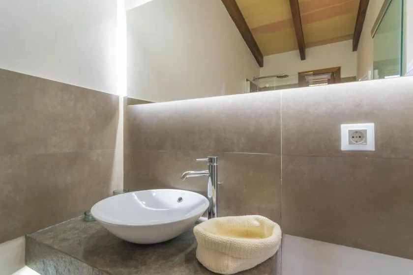 A bathroom vanity with a white vessel sink and stone countertop.