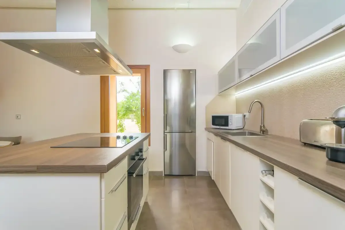 A bright modern kitchen with a central island and stainless-steel refrigerator.