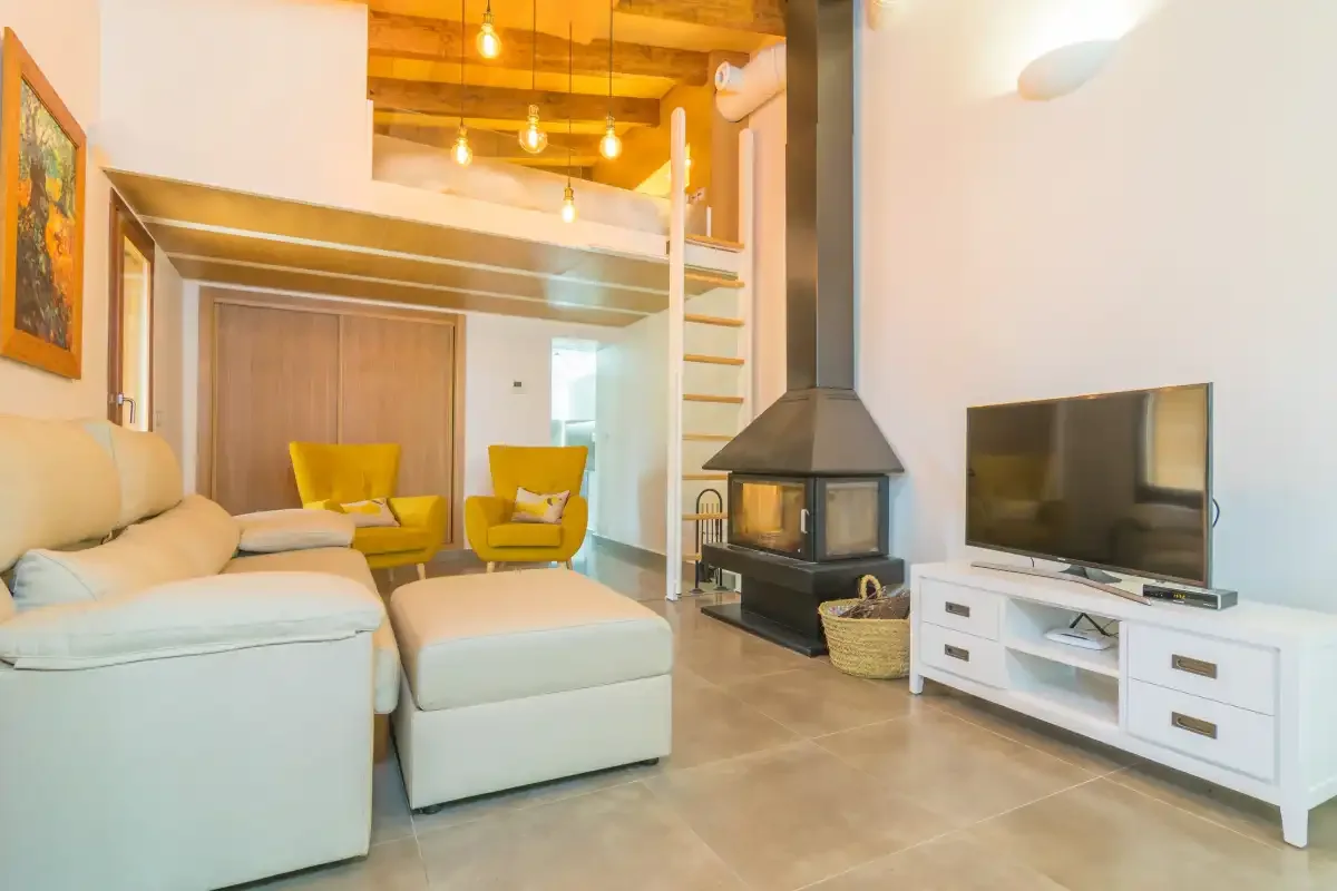 A living room with seating, a television, and a freestanding fireplace.