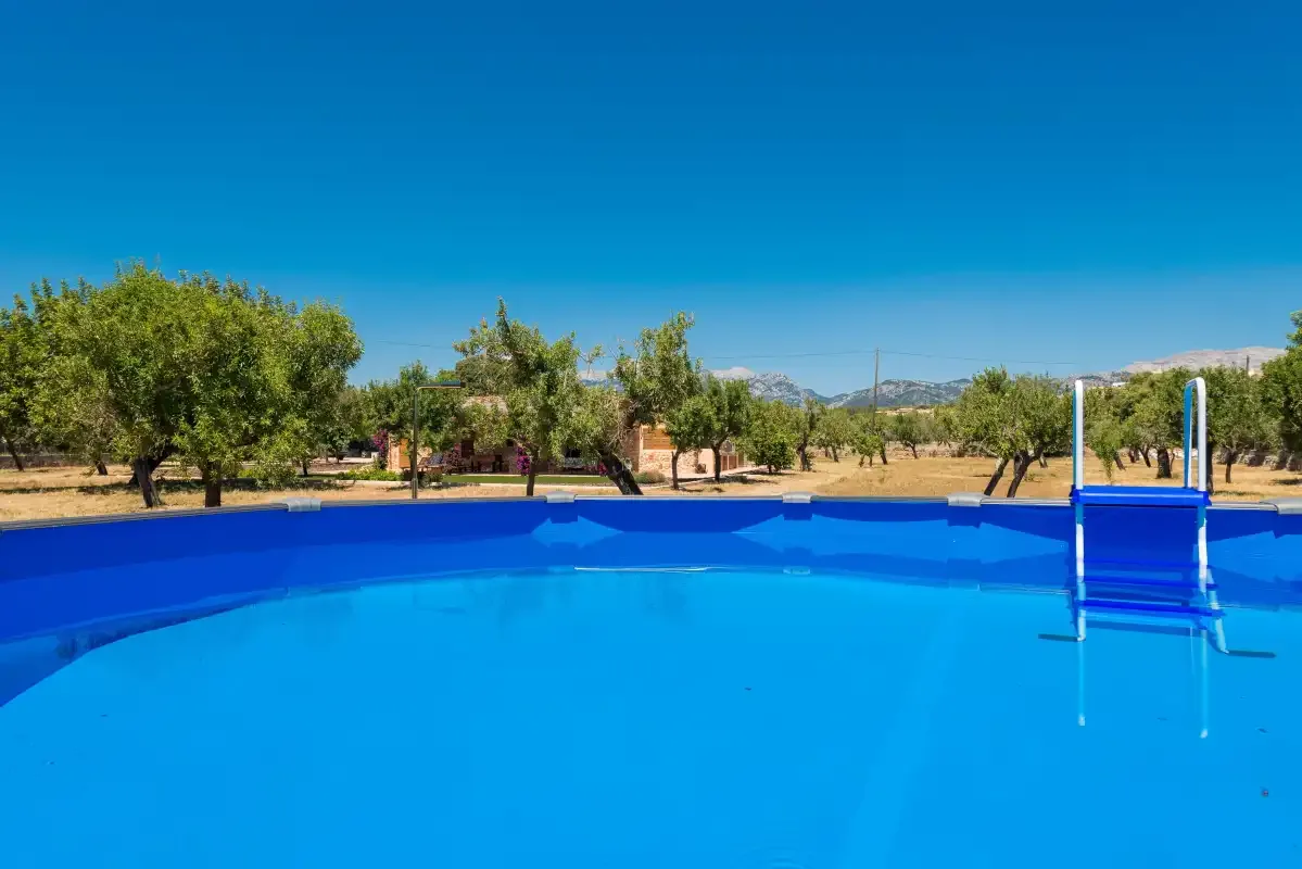 A bright blue swimming pool sits outdoors beneath a clear sky.