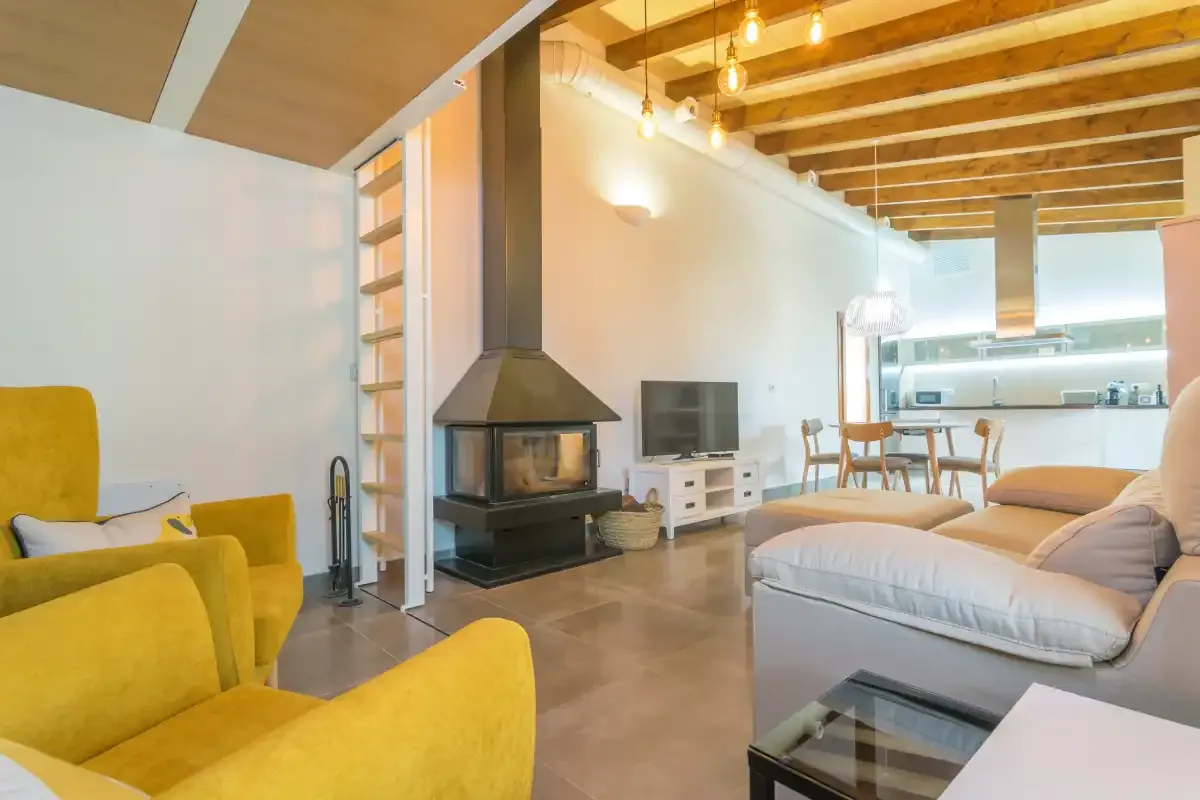 A bright living room with yellow seating, a fireplace, and a television.