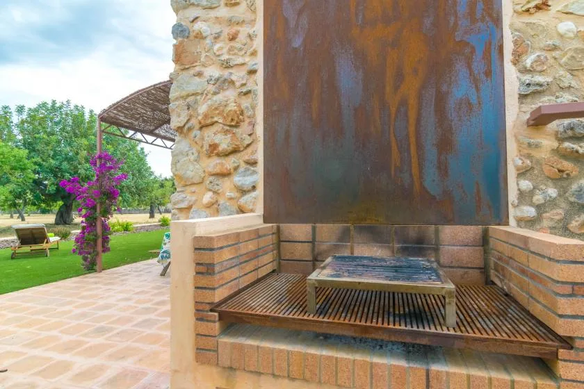 An outdoor water feature sits beside a stone wall, with a tiled patio and garden nearby.