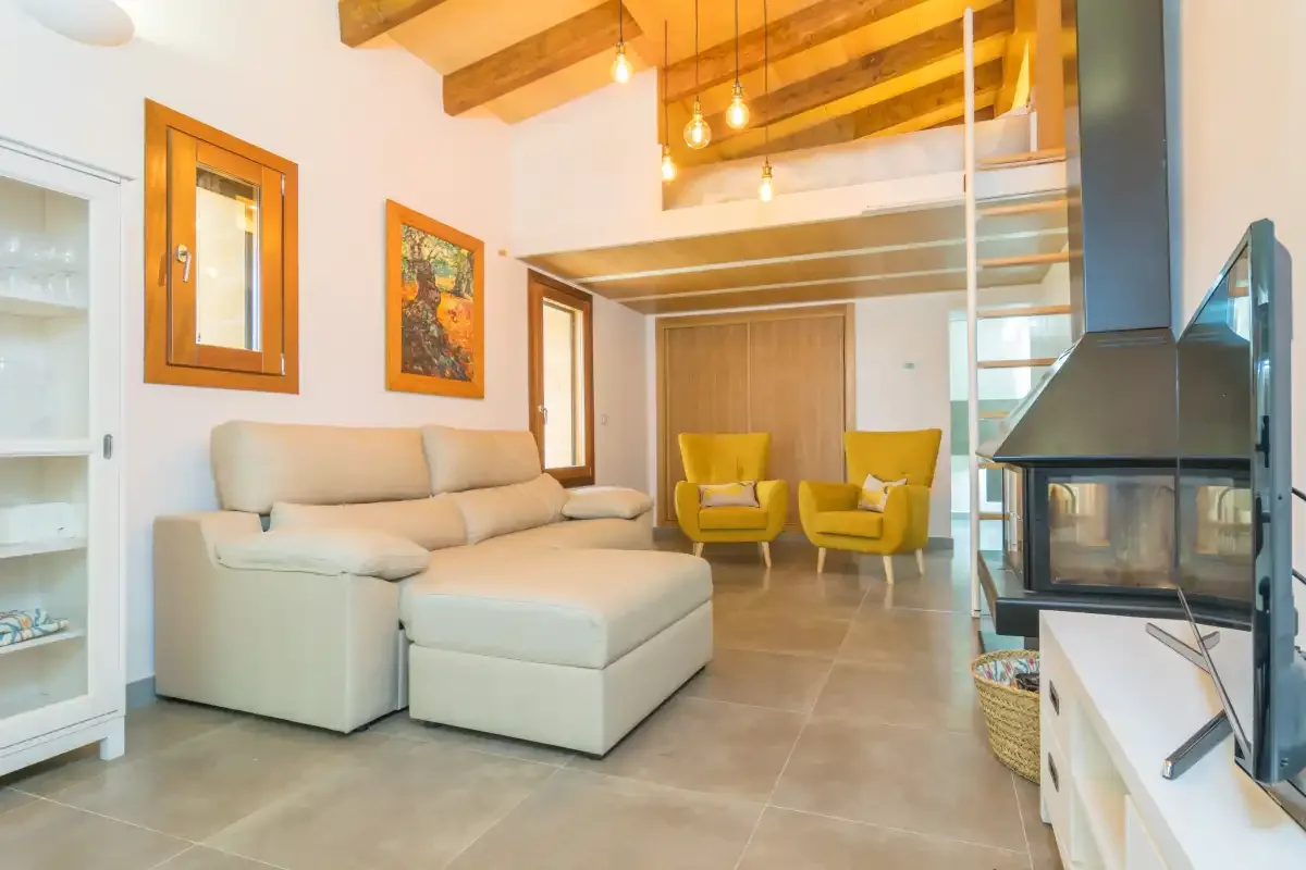 A living room with a sectional seating area, two yellow chairs, and a fireplace.