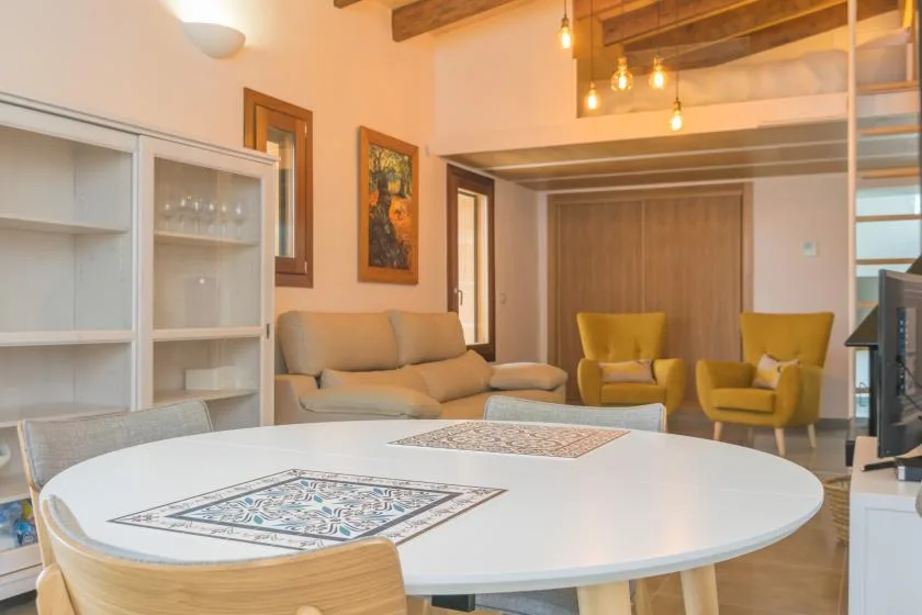 A bright living room with a sofa, two armchairs, and a round table.