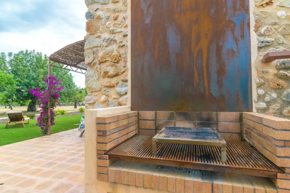 An outdoor patio features a built-in barbecue beside a garden.