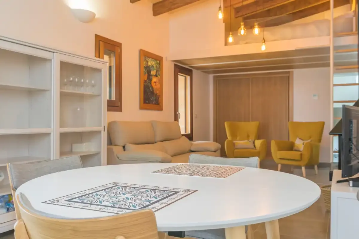 A living and dining area with a round table, seating, and framed wall art.