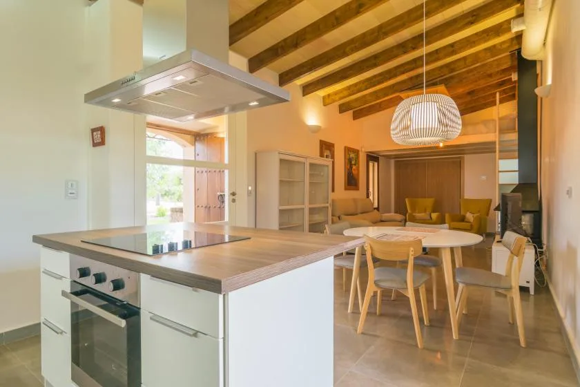 An open kitchen and dining area with a central island and exposed ceiling beams.