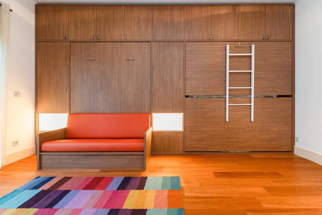 Un mueble empotrado de madera con una zona de asiento roja y una alfombra colorida.