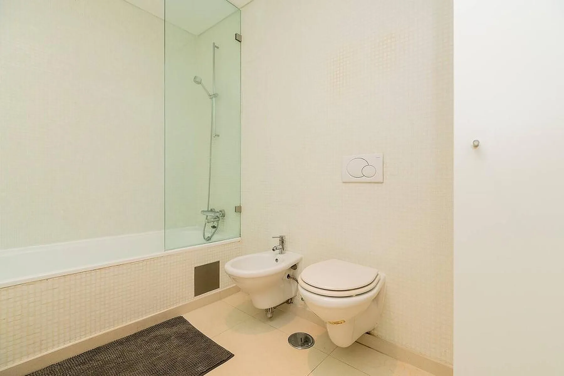 Un baño luminoso con ducha, inodoro y bidé.