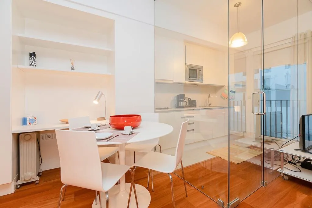 Un interior de estudio luminoso con mesa de comedor y cocina compacta.