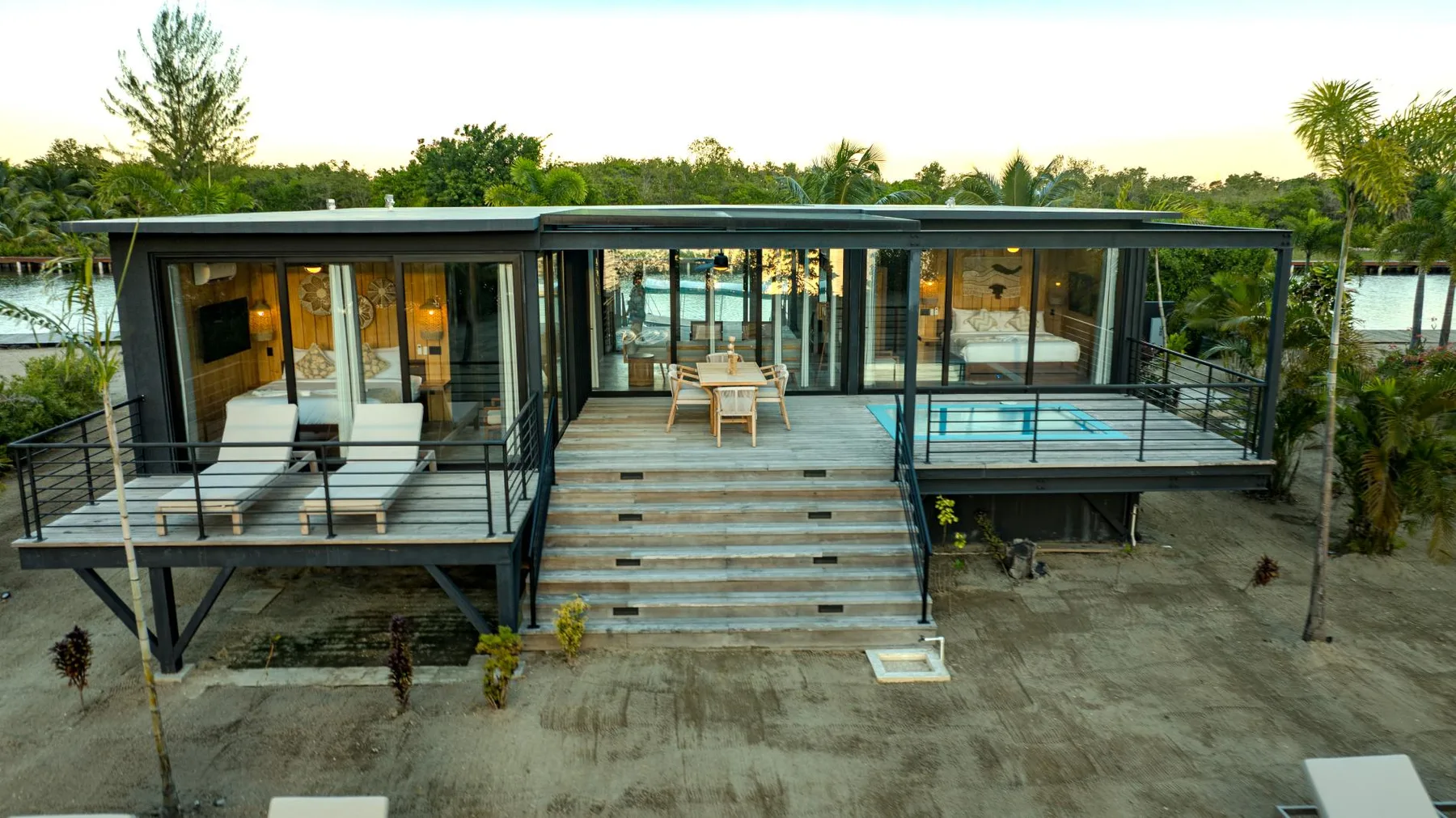 A modern glass-fronted house has a broad wooden deck and outdoor seating.