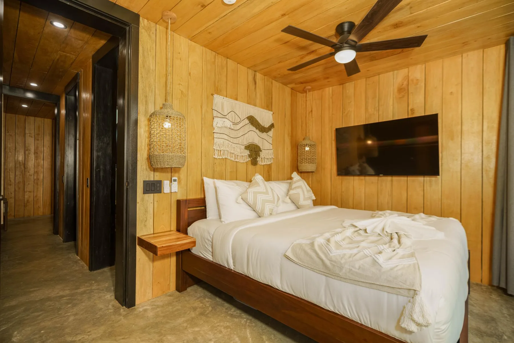 A bedroom with a neatly made bed and a wall-mounted television.