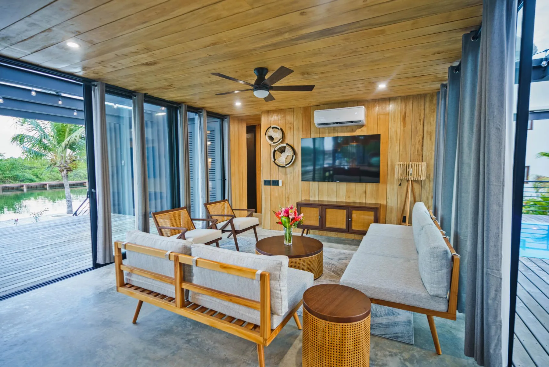 A wood-paneled living room with seating around a coffee table and wide glass doors.