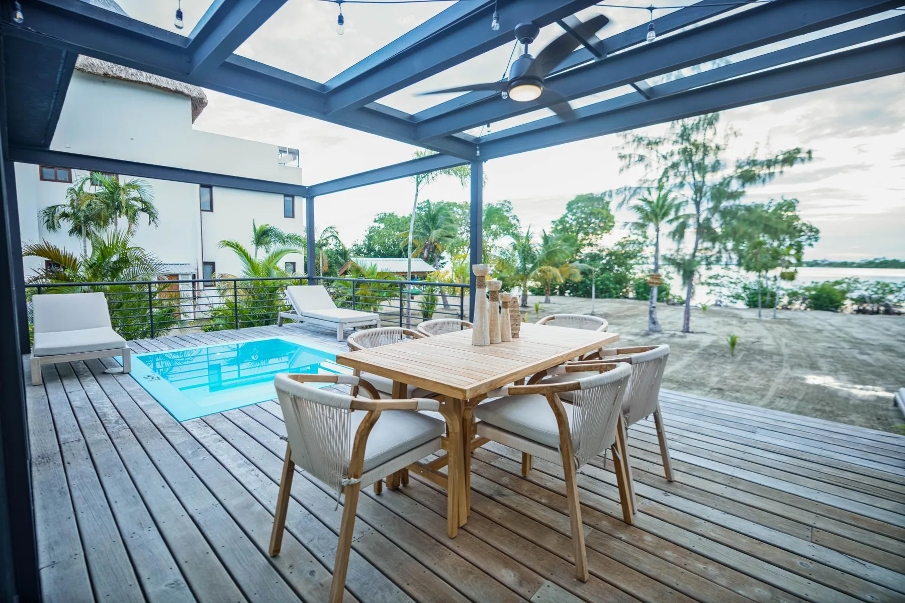 A covered outdoor dining area overlooks a small pool and landscaped grounds.